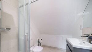 A modern bathroom with a glass shower enclosure, a white toilet, and a sink with a mirror.