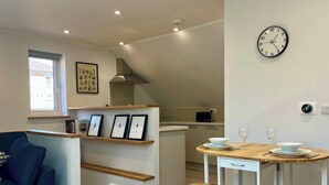 A modern kitchen with a round table, a clock, and framed pictures on the wall.