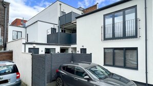 Ein modernes, zweistöckiges Haus mit Balkon, einem Auto auf der Auffahrt und einem verschlossenen Eingang.
