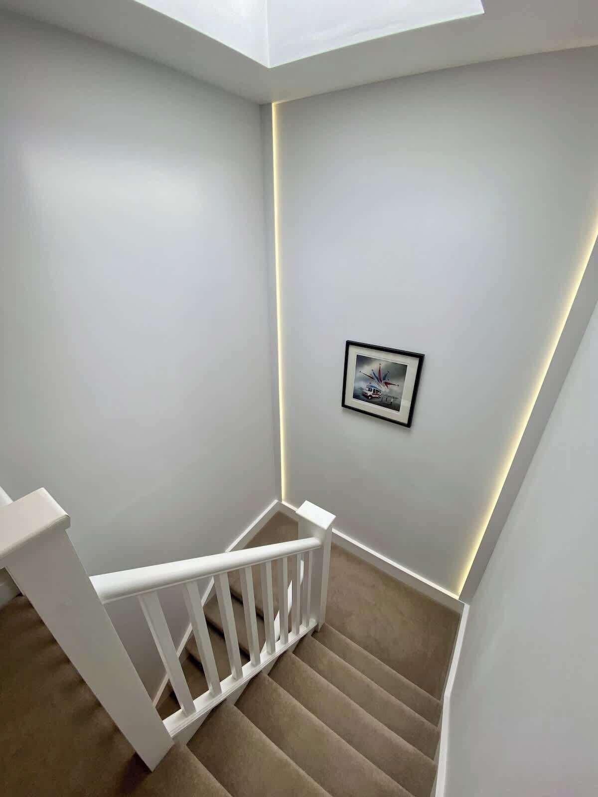 Een trap met witte leuningen en een schilderij aan de muur.