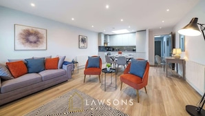 A modern living room with a sofa, chairs, and a dining area. - Central Windsor Gem | 1BR Penthouse + Balcony (Windsor)