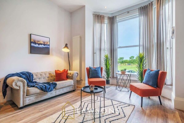 A living room with a sofa, two armchairs, a coffee table, a lamp, and a painting on the wall.