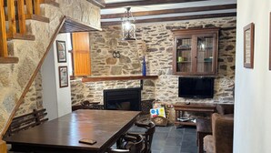 Una sala de estar acogedora con pared de piedra, muebles de madera y chimenea.