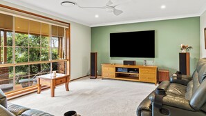 A living room with a large window, a flat-screen TV, wooden furniture, and a ceiling fan. - Heavenly Hideaway at Lovedale Private Pool and Spa (Allandale)