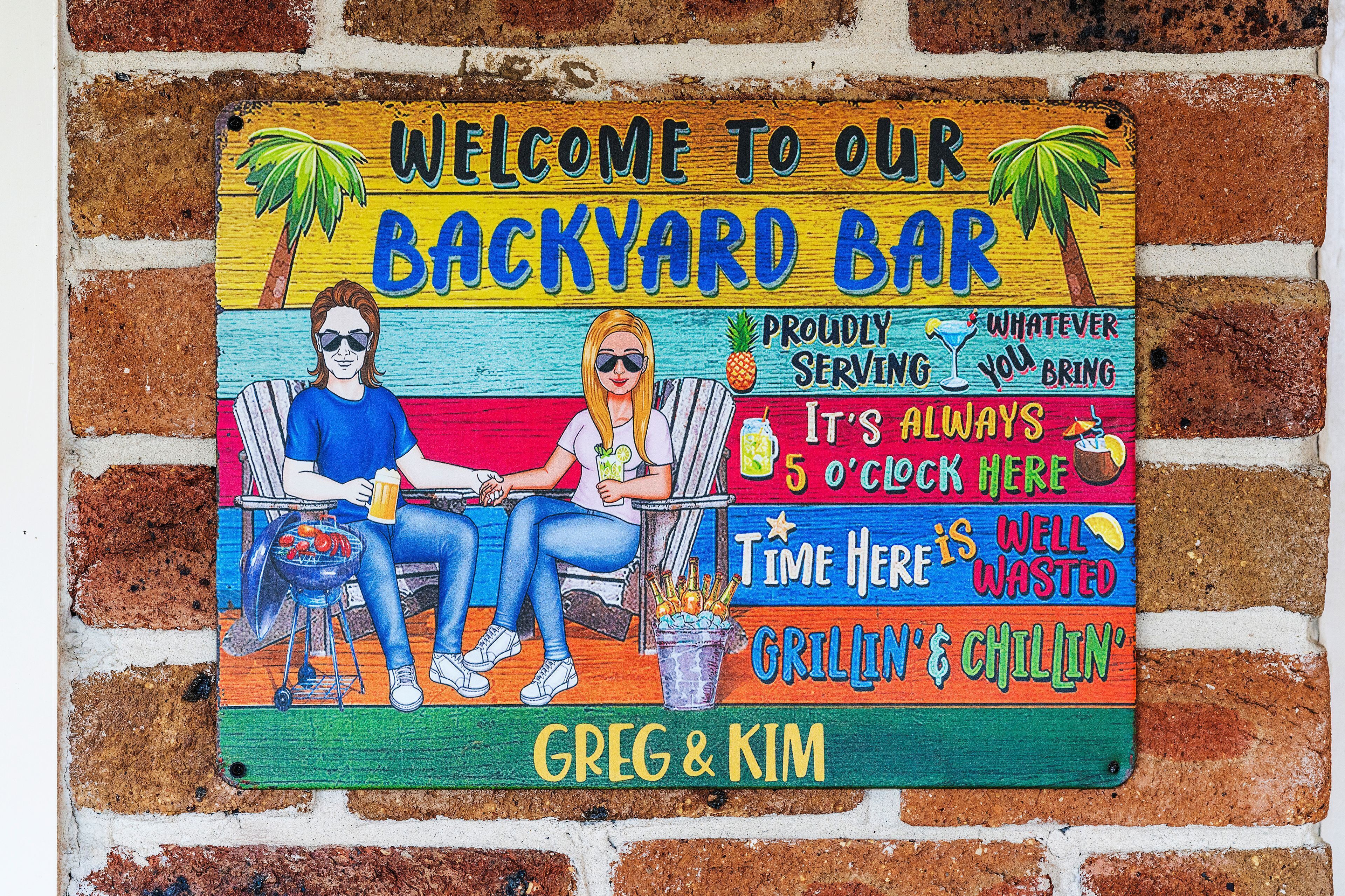 A colorful sign for a backyard bar with two people seated, a grill, and a drink.