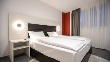 A modern hotel room with a large bed, a bedside table, and a nightstand.
