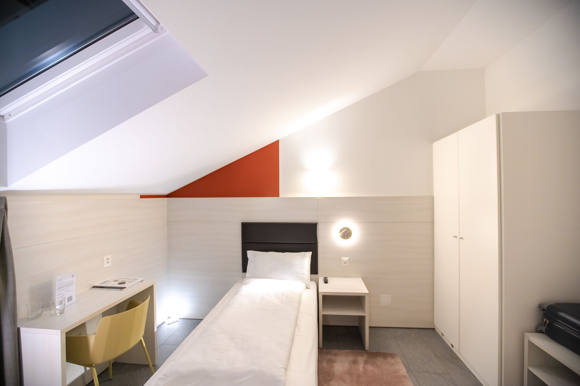 A modern bedroom with a bed, desk, and wardrobe.