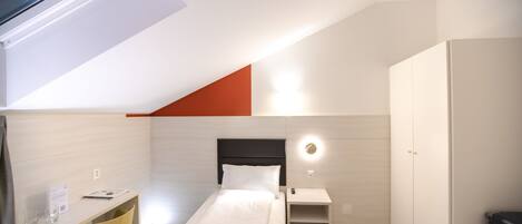 A modern bedroom with a bed, desk, and wardrobe.