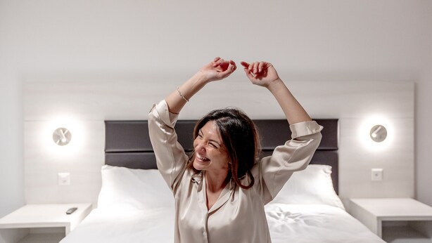 Une chambre d’hôtel avec un lit, des tables de chevet et des horloges fixées au mur.
