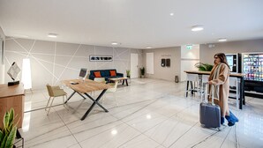 Un hall d’hôtel moderne comprenant un comptoir d’accueil, un espace salon et des bornes d’enregistrement automatique.