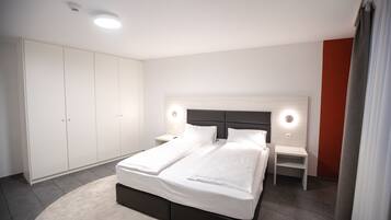 Un dormitorio moderno con una cama grande, un armario blanco y mesitas de noche.