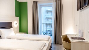 Une chambre d’hôtel avec un lit, un bureau et une vue sur un balcon.