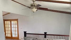 A living room with a gray sectional sofa, a round coffee table, and a ceiling fan.