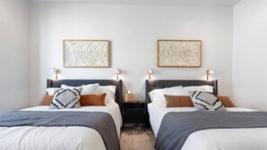 Une chambre double avec deux lits, chacun doté d’une tête de lit, de tables de chevet et de lampes. Deux œuvres d’art sont accrochées au mur au-dessus des lits.