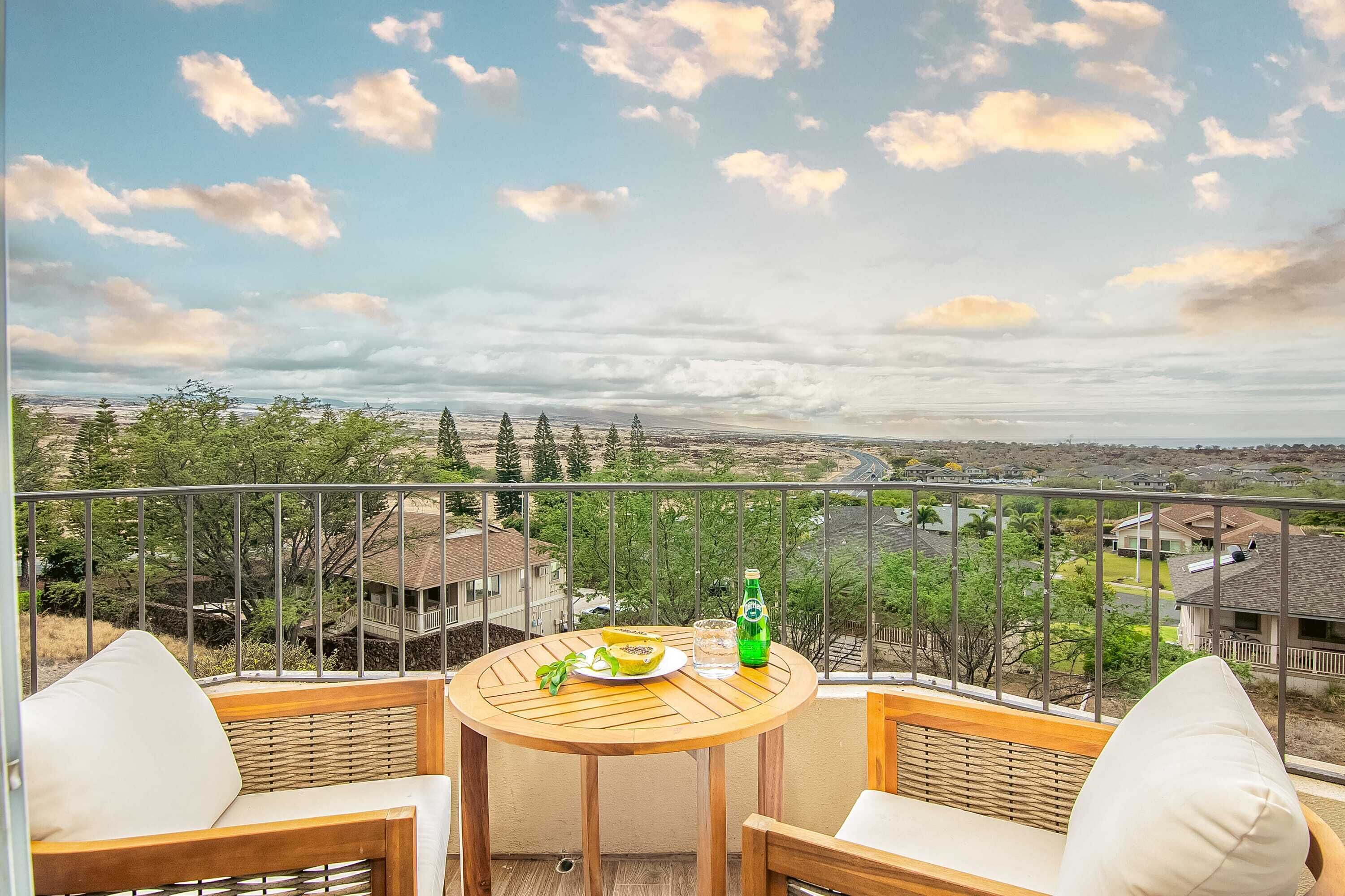 A balcony with a round wooden table, two wicker chairs, and a bottle of water.