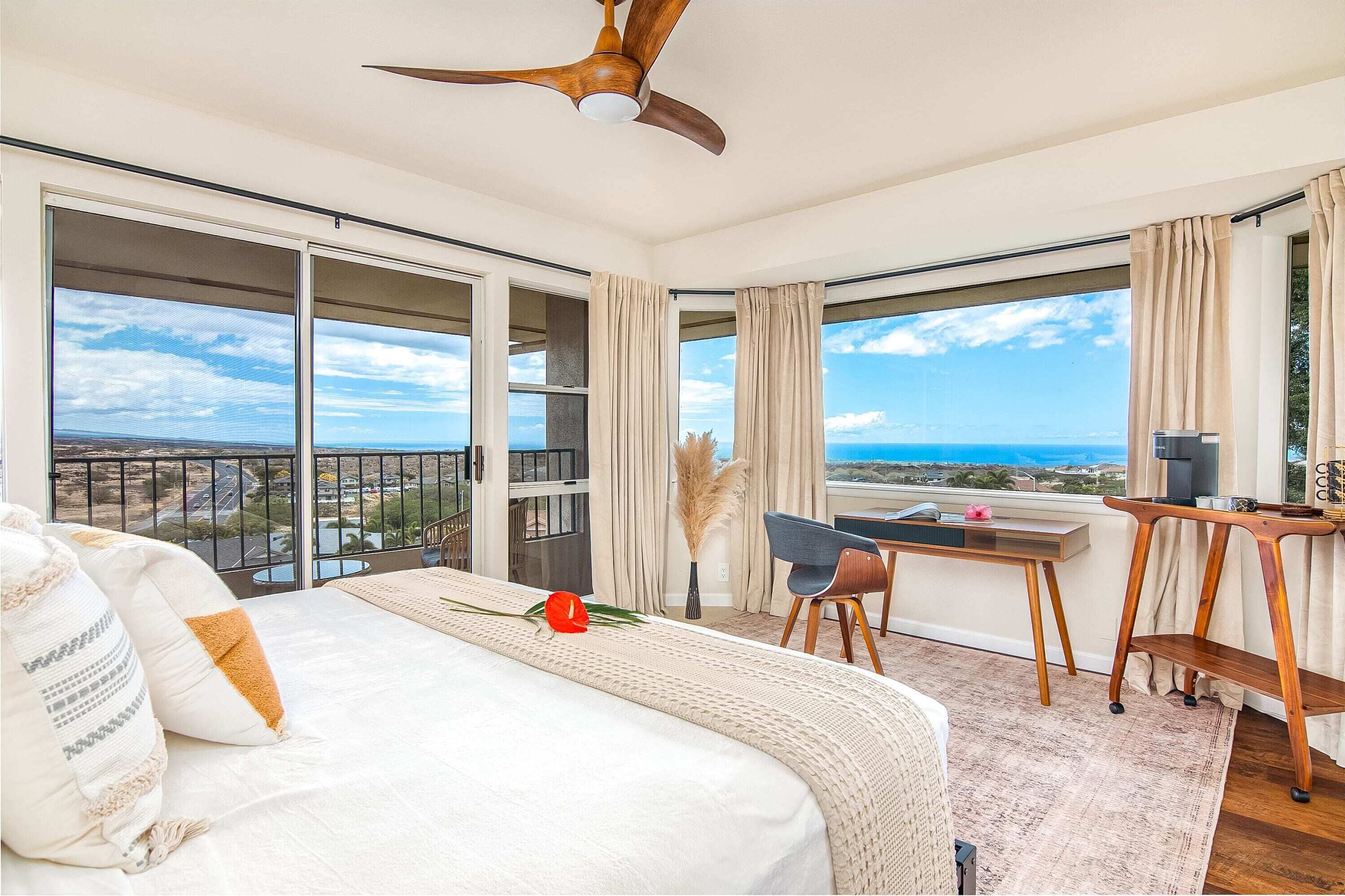 A hotel room with a large bed, a desk, and a view of the ocean.
