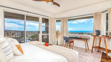 A hotel room with a large bed, a desk, and a view of the ocean.