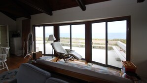 A room with a large sliding glass door leading to a balcony with a view of the beach. - 36 Salt Marsh Rd (Sandwich)