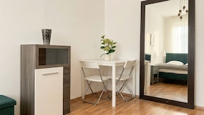 A room with a desk, two chairs, a potted plant, a mirror, and a bed with a green headboard. - Big 3BR shared Apt. Perfect location (Vienna)