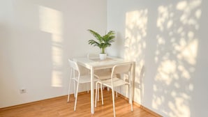 A white table with four chairs, a potted plant, and a small table. - Big 3BR shared Apt. Perfect location (Vienna)