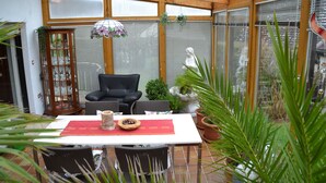 Um solário com mesa de jantar, cadeiras e plantas em vasos.