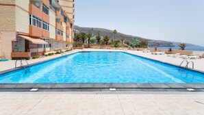 A swimming pool with a view of a hillside and a building with balconies. - Frontline Duplex Las Arenitas with pool (Candelaria)