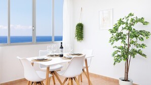A dining area with a table set for two, a bottle of wine, and a view of the sea through large windows. - Frontline Duplex Las Arenitas with pool (Candelaria)
