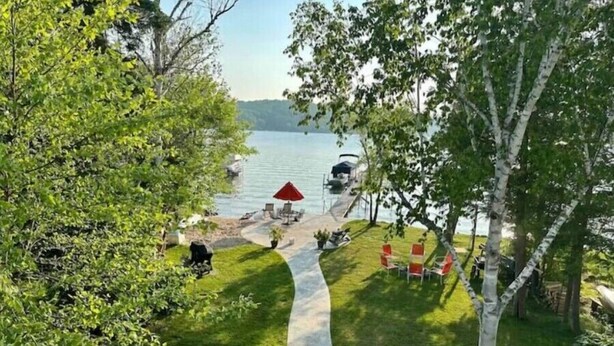 Um alpendre à beira do lago com mesas ao ar livre e um caminho que leva à água.