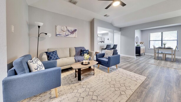 Un salon moderne comprenant un canapé, des fauteuils, une table basse et un coin repas avec une table et des chaises.