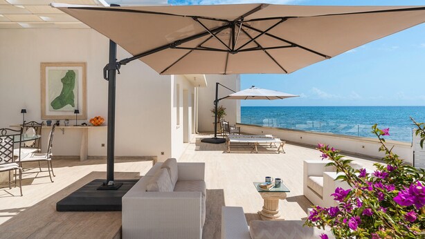 An outdoor seating area with a view of the sea, featuring a sofa, chairs, and umbrellas. - Jacuzzi and direct access to the sea, Avola -  DiCasaInSIcilia (Avola)