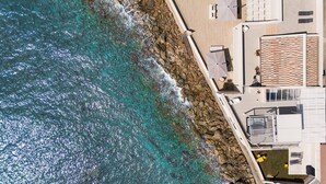 An aerial view of a coastal hotel with a rocky shoreline, outdoor seating, and a tiled roof. - Jacuzzi and direct access to the sea, Avola -  DiCasaInSIcilia (Avola)