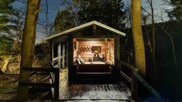 Eine kleine Holzhütte mit Veranda, Innenraum mit Bett und Tisch sichtbar.