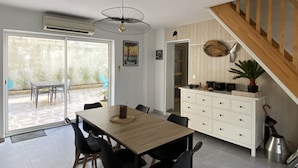 A dining area with a wooden table and chairs, a white cabinet with drawers, and a staircase leading to another level.
