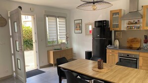A modern kitchen with a dining area, featuring a wooden table, black chairs, a black refrigerator, and a microwave.