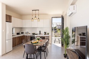 Une cuisine moderne avec des meubles blancs, une table à manger avec des chaises et une grande fenêtre.