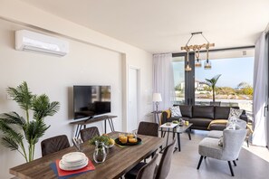 Una sala moderna con una televisión de pantalla plana, una mesa de comedor, sillas y un sofá.
