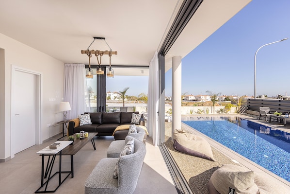 Un salon moderne avec un canapé, une table basse et une vue sur une piscine.