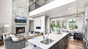 A modern kitchen with a large island, stone accent wall, and a fireplace. - Unbelievable VIEWS indoor pool cabin (Sevierville)