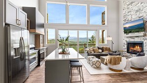 A modern kitchen with a central island, a dining area with a view, and a cozy seating area with a fireplace. - Unbelievable VIEWS indoor pool cabin (Sevierville)