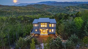 A two-story house with a large front porch, surrounded by dense forest and mountains in the background. - Unbelievable VIEWS indoor pool cabin (Sevierville)
