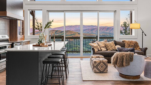 A modern kitchen with a large island, a dining area with a view, and a cozy seating area with a sofa and ottoman. - Unbelievable VIEWS indoor pool cabin (Sevierville)