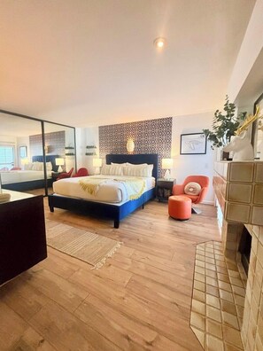 Een moderne slaapkamer met een groot bed, een open haard en een spiegel.