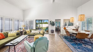 A spacious living room with a green sofa, a blue armchair, and a dining area with a round table and chairs. - The PERFECT Desert Getaway / La Quinta Resort (La Quinta)