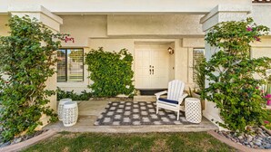 A covered porch with a white chair, a patterned rug, and climbing plants. - The PERFECT Desert Getaway / La Quinta Resort (La Quinta)