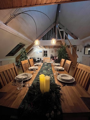 A dining area with a long table set for a meal, wooden chairs, a Christmas tree, and a ceiling with exposed beams. - Spacious apartment over 2 floors in a central location with castle view, wallbox (Saarburg)
