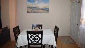 A dining area with a table and chairs, a painting on the wall, and a door. - Belle Zoon Villa (Gros Islet)