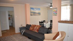 A living room with a sofa, a chair, a dining table with chairs, a cabinet, and a painting on the wall. - Belle Zoon Villa (Gros Islet)