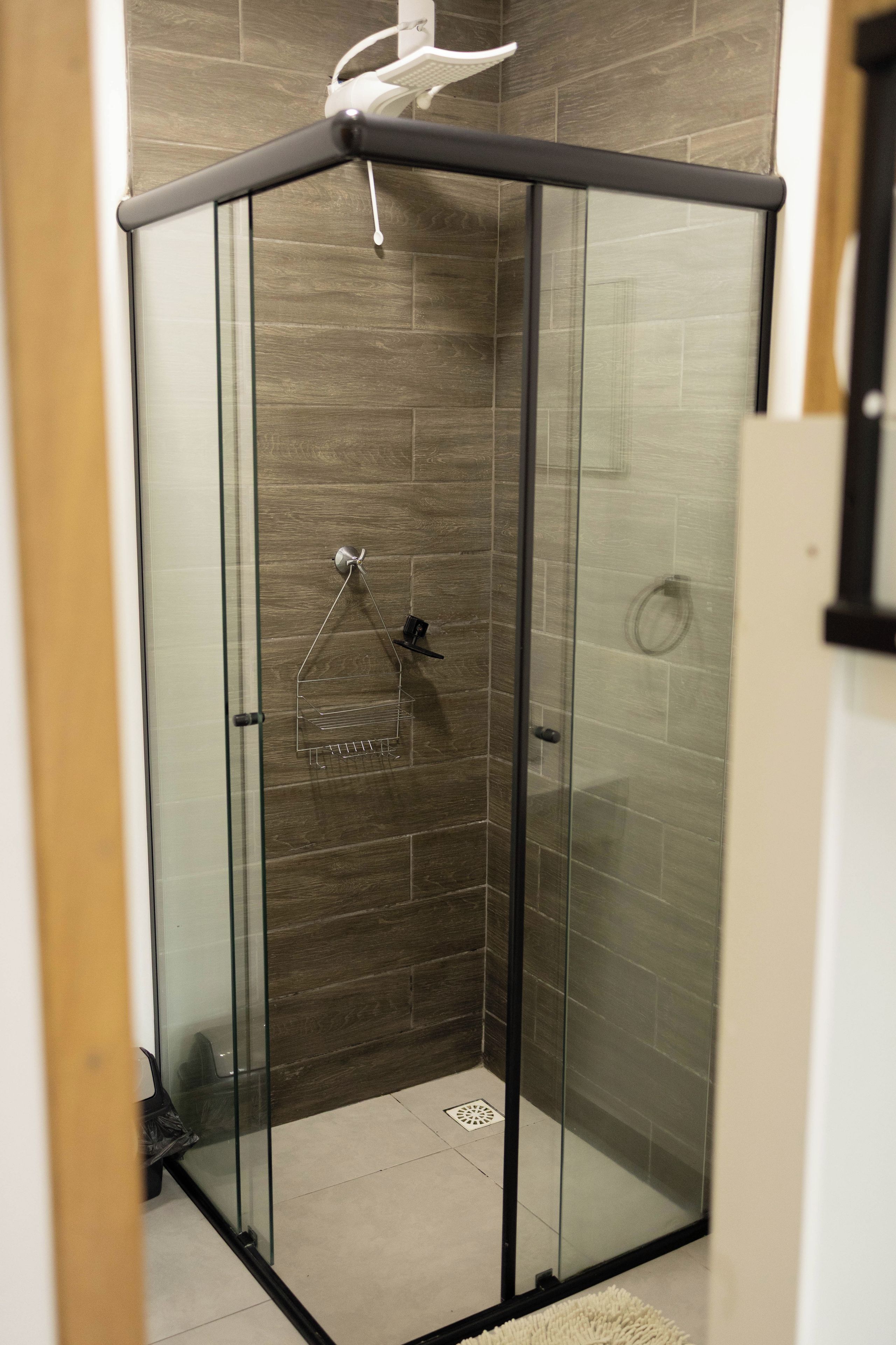 Eine gläserne Duschkabine mit modernem Design, ausgestattet mit einer Dusche und einem Wandmontage-Händetrockner.