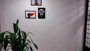 A room with a white wall, three framed pictures, a potted plant, and a mat on the floor. - pousada São José (Joinville)