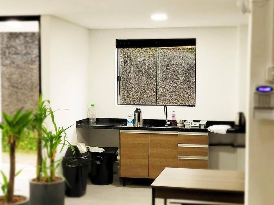 Eine moderne Küche mit schwarzem Arbeitsplatz, Holzschränken und einem Fenster mit strukturierter Aussicht.